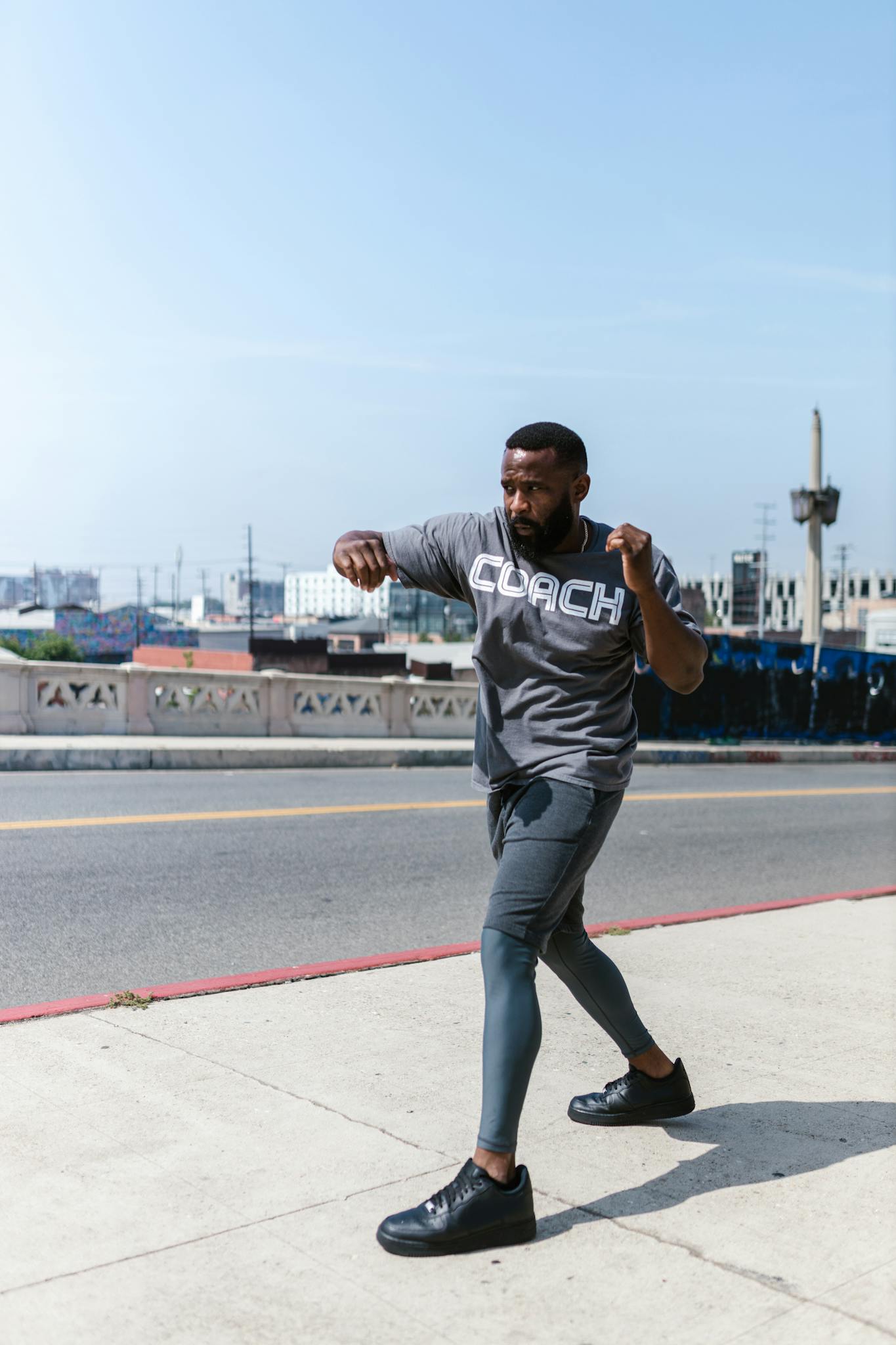 A fit African American man performing outdoor exercises on a street, showcasing healthy living.